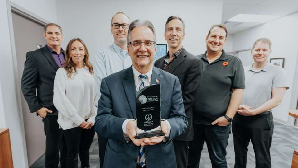 Tom D'Amico holding the EDTECH award, team members behind him.