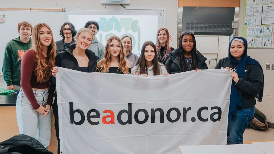 Students holding a flag saying Be a Donor