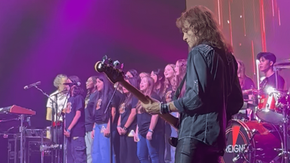 Musician playing cords and school choir singing in the back