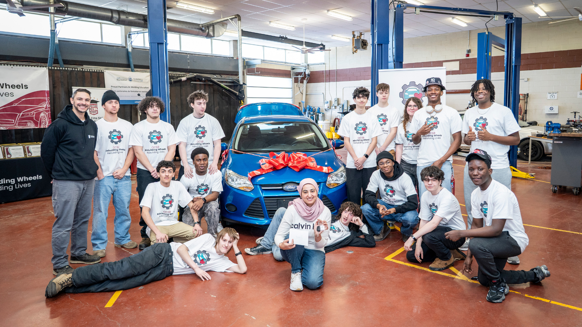 OCSB students who worked on the rebuillding wheels project beside ther car they fixed.