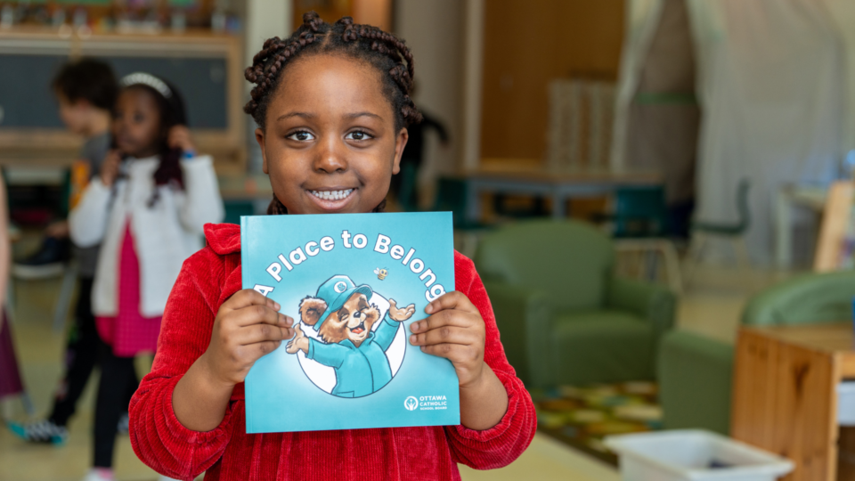 A student holding the book "A Place to Belong"